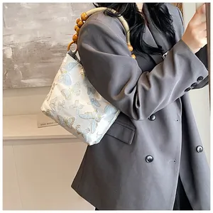 Detail der Schmetterlingsstickerei auf der Tasche mit einzigartigem Holzperlengriff