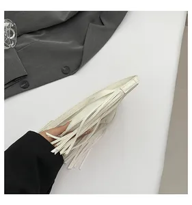 Detail of white lychee leather texture and long fringe tassels on a vintage crossbody bag