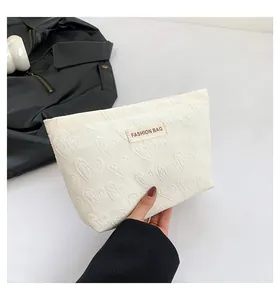 Detailansicht der cremefarbenen Kosmetiktasche mit 3D-Herzprägung und Modelabel