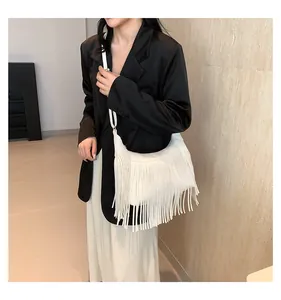 Dettaglio di una borsa a tracolla bohémien bianca con lunghe frange su modella