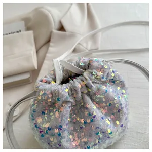 Close-up of iridescent sequins and drawstring detail on white bucket bag with thin strap