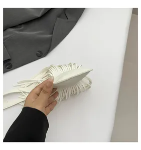 Close-up of white pebble leather crossbody bag with fringe detailing and flat structure