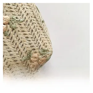 Close-up of woven bag featuring delicate floral embroidery and white lace overlay detail