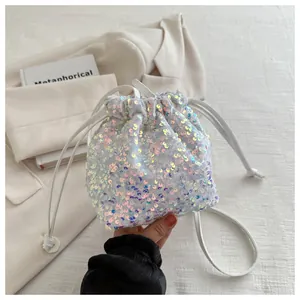 Detailed view of white sequined bucket bag with drawstring closure on beige background