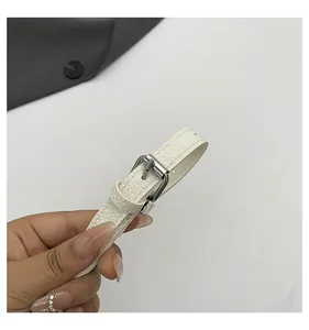 Detail showing white lychee pattern leather strap with silver buckle and fine stitching