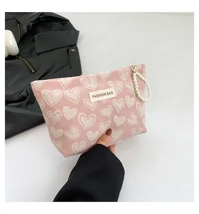 Detail der rosa Canvas-Handtasche mit Herzmuster und Perlen-Tragegurt für die Kosmetiktasche