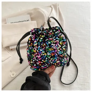 Detailed view of a rainbow sequin bucket bag with black drawstring closure and slim strap