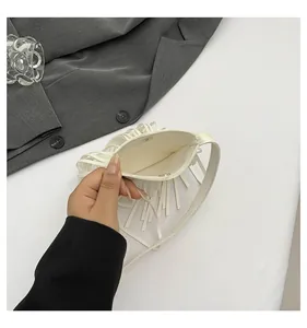Detail view of small white crossbody bag with fringe tassels and magnetic snap closure
