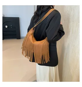 Borsa a tracolla bohémien marrone con frange indossata da modella in interno