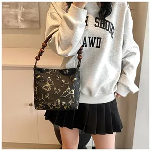 Detailansicht der schwarzen Stoffhandtasche mit goldenem Schmetterling und Perlengriff