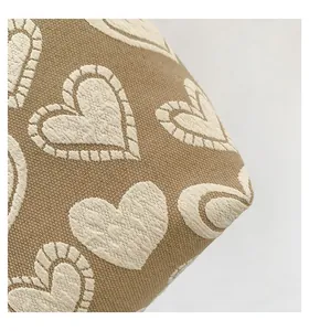 Makroaufnahme von beigem Strickstoff mit weißen Jacquard-Herzmustern und Texturnähten