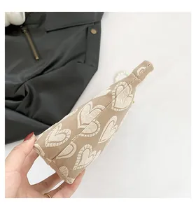 Detailansicht der khakifarbenen Canvas-Tasche mit 3D-Herzen und eleganter Perlenkette