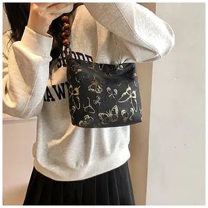 Detail der schwarzen Achseltasche mit goldenen Schmetterlingen und Holzperlengriff