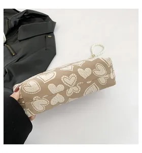 Nahaufnahme der khakifarbenen Segeltuch-Kosmetiktasche mit Herzmuster und Perlengriff