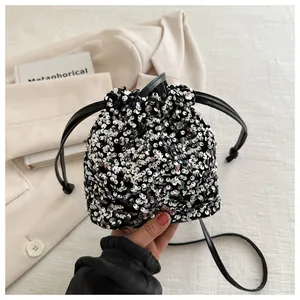 Close-up of silver sequin bucket bag featuring a black drawstring closure and shiny texture