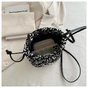 Detailed view of black sequin bucket bag showing interior space for wallet and smartphone
