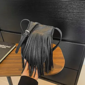 Vintage black lychee leather crossbody phone bag with tassel detail on wood background