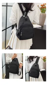 Close-up of black nylon chest bag with multiple zip pockets and plastic buckle detail