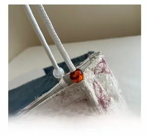 Detail showing red butterfly embroidery on cream fabric with amber beads on the bag