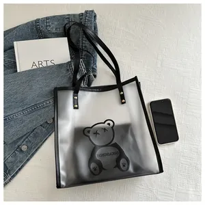 Detail of translucent tote bag featuring black cartoon bear print and rivet shoulder straps