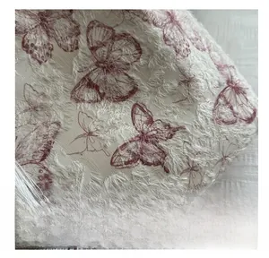 Close-up of jacquard fabric with red butterfly embroidery and soft fringe texture