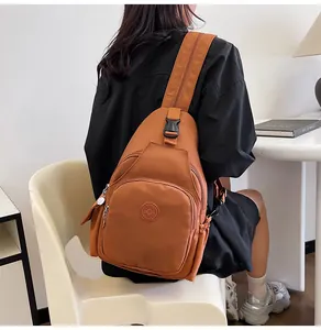 Detail of a brown nylon chest bag with multiple zipper compartments and a sports logo