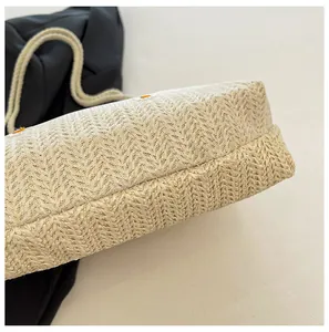 Détail d'un sac de plage en paille avec broderies florales orange et bandoulière en coton
