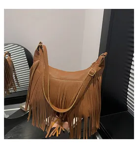 Dettaglio macro della borsa a sella marrone con lunghe frange e fibbia in metallo oro