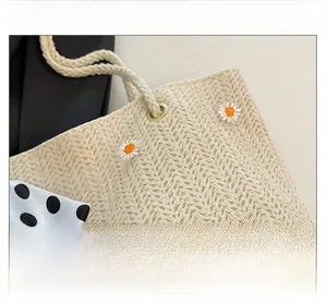 Détail du sac en paille avec broderie marguerite, anses en corde et ruban à pois