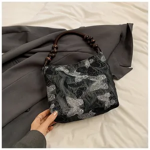Detail von schwarzem Jacquard-Stoff mit Silberfalter-Mustern und Holzperlengriff