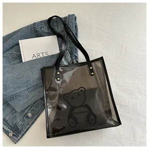 Detailed view of black translucent PVC tote bag with bear print on a stylish white bed