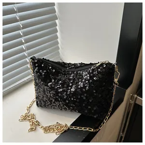 Makroansicht der schwarzen Pailletten-Beuteltasche mit goldener Kette auf Fensterbank