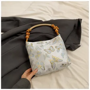 Detailansicht der Stoffhandtasche mit Schmetterlingsstickerei und Holzperlengriff für Damen