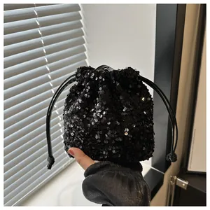 Close-up of shiny black sequin bucket bag with drawstring handle and glitter texture
