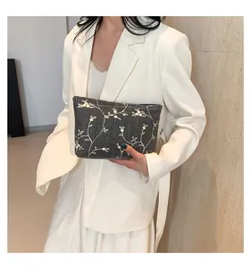 Detailed view of dark gray fabric handbag featuring white floral embroidery patterns
