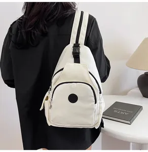 White nylon chest bag on a model featuring a black logo and contrast zippers in a room