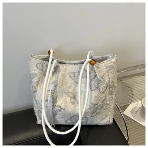 Detail of cream tote bag featuring grey butterfly patterns and elegant tassel charm