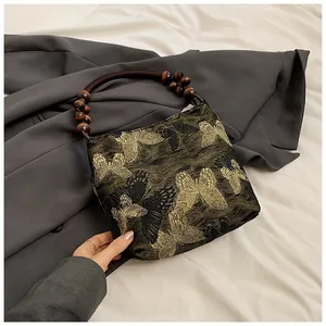 Detail der Schmetterlingsstickerei und dunkle Holzperlengriffe an Vintage-Tasche