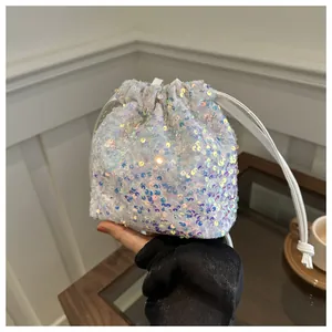Macro detail of iridescent sequins and drawstring closure on mini white bucket bag