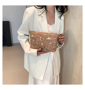 Detailed embroidery of white and green flowers on a brown straw-textured clutch bag