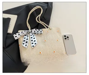 Détail du sac cabas en paille avec broderie marguerite et anse en foulard à pois élégant