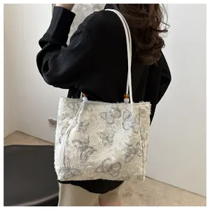 Detail of white butterfly jacquard tote with textured fabric and elegant tassel charm