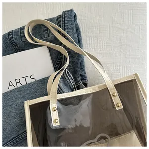 Detail of transparent PVC tote bag with beige leather handles and gold rivet accents