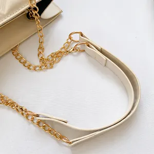 Detail van de beige PU-lederen riem en gepolijste goudkleurige ketting van deze kleine tas