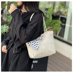 Détail du sac cabas en paille tissée avec motifs floraux et foulard à pois