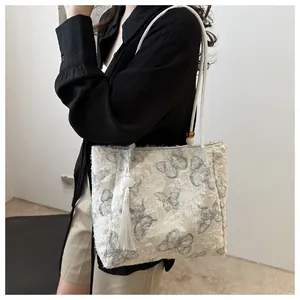 White butterfly pattern tote bag with fringed texture worn by a model on shoulder