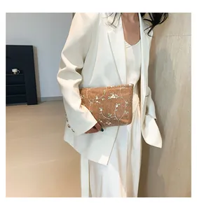 Detail of woven straw clutch with delicate floral embroidery on natural light brown material