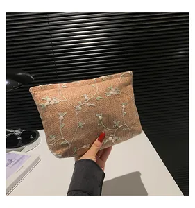 Close-up of hand-held woven pouch with white floral embroidery and high-quality texture