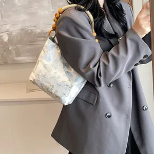 Elegante weiße Schultertasche mit Schmetterlingsstickerei und Holzperlen-Schultergurt