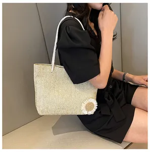 Détail du cabas en paille avec anses en corde blanche et petite fleur de marguerite